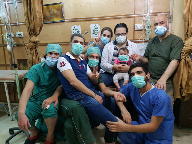 Hamza al-Kateab, in white coat, holding his daughter Sama, with fellow hospital staff in rebel-held Aleppo.
