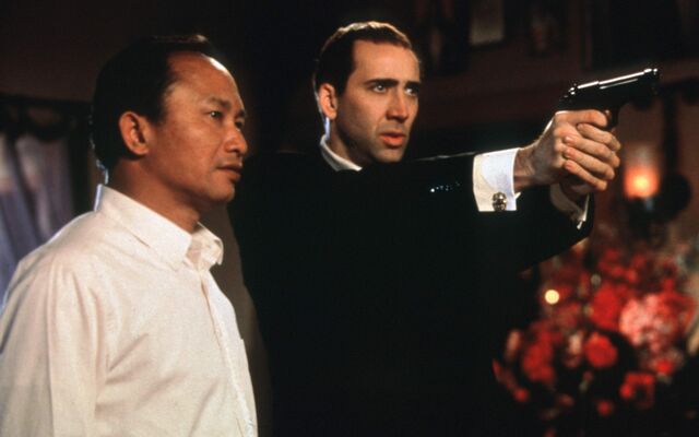 John Woo watches Nicolas Cage take aim in a production still from Face/Off (1997).